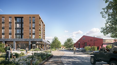 A street view of a modern building with a red building in the background and a green car on the road.