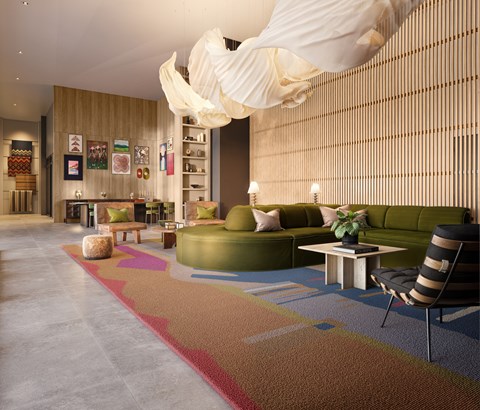 A modern living room with a green couch and a colorful rug.