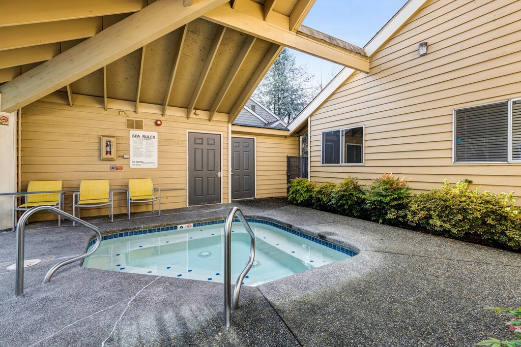 the pool is under the porch of a house with yellow chairs