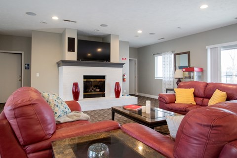 A living room with red leather couches and a fireplace.