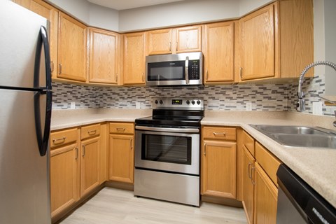 A kitchen with wooden cabinets and a black refrigerator.
