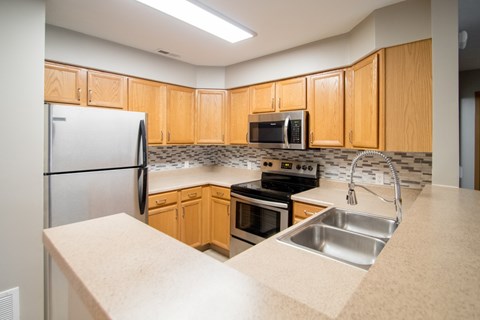 A kitchen with wooden cabinets and a stainless steel refrigerator.