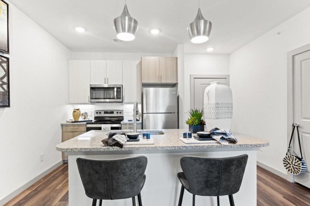 A kitchen with a table and two chairs.