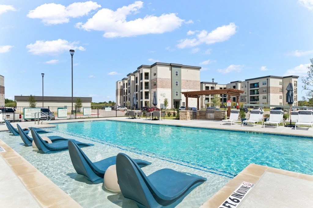 A pool with blue chairs and a building in the background.