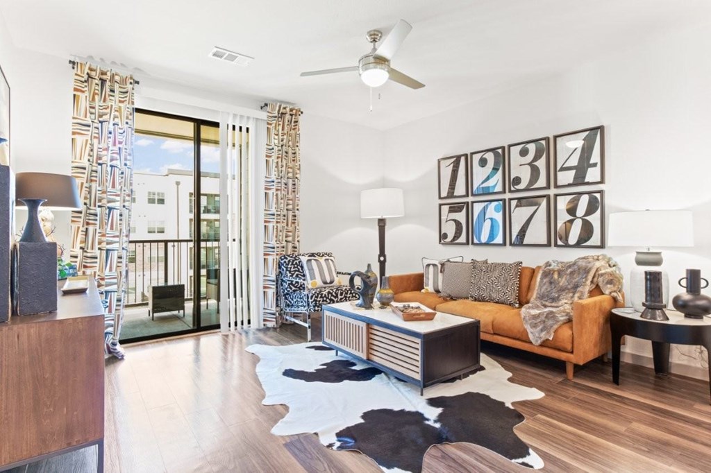 A living room with a cowhide rug and a large numbered wall art.
