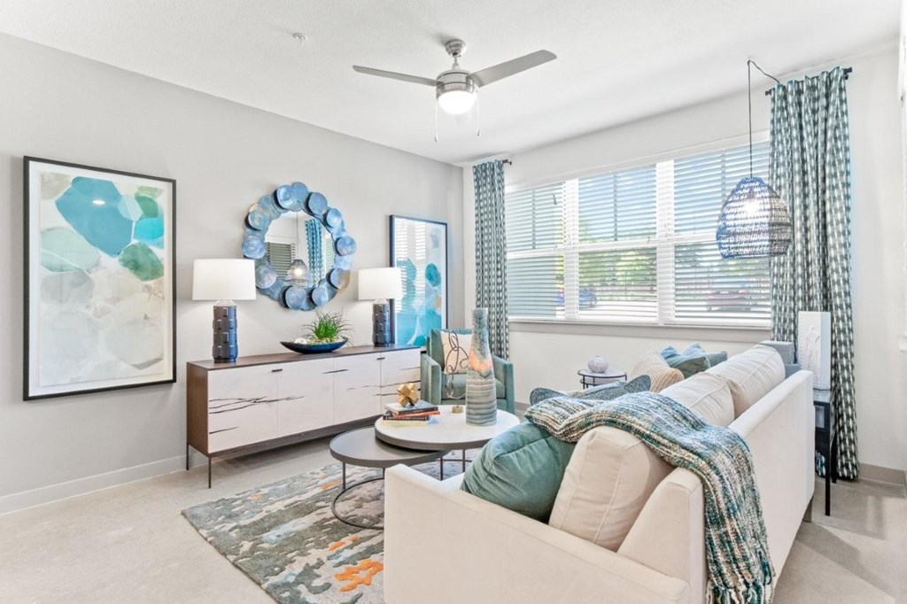 A living room with a white couch and a blue wreath on the wall.