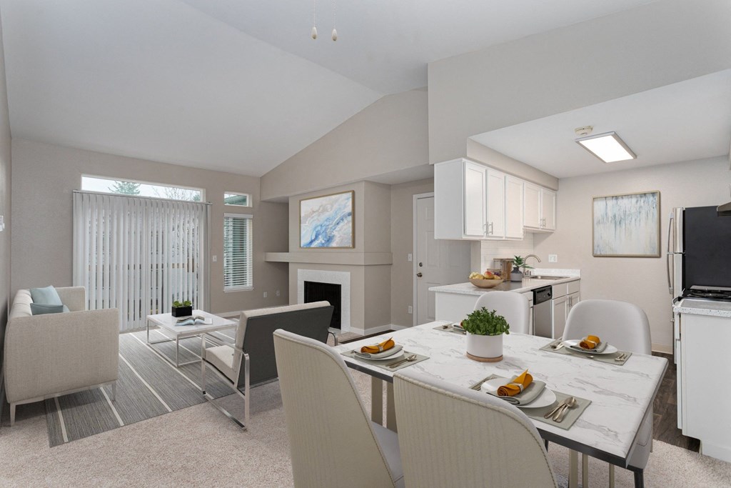 a living room with a dining room table and chairs and a fireplace in the background