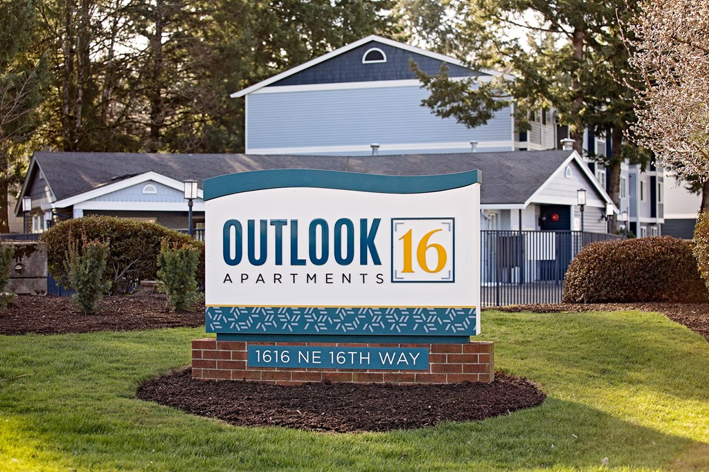 a sign that says outlook 16 apartments with a house in the background