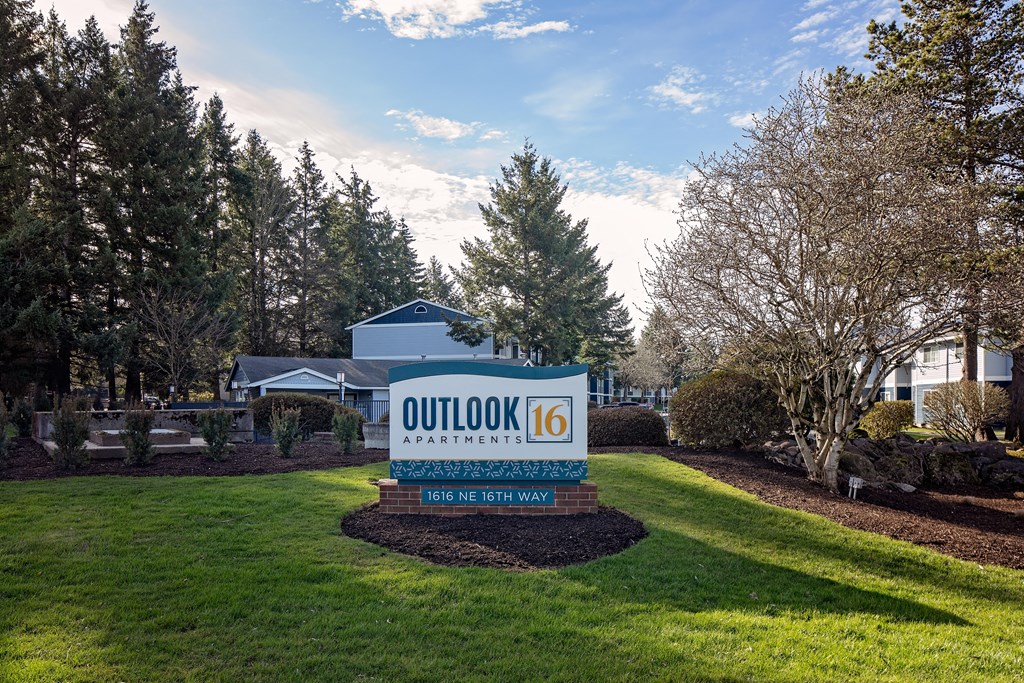 a sign that says outlook 16 with a house and trees in the background