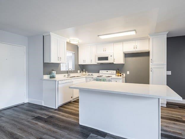 A kitchen with white cabinets and a white island.