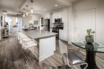 A modern kitchen with a long island and white chairs.