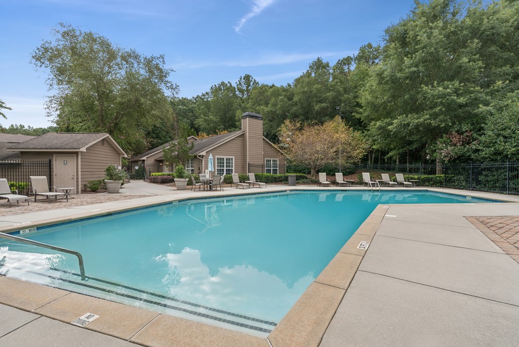 A swimming pool surrounded by trees and a house.