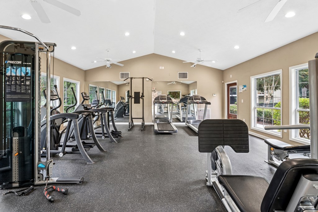 A spacious gym with a variety of equipment including treadmills, elliptical machines, and a weight machine.