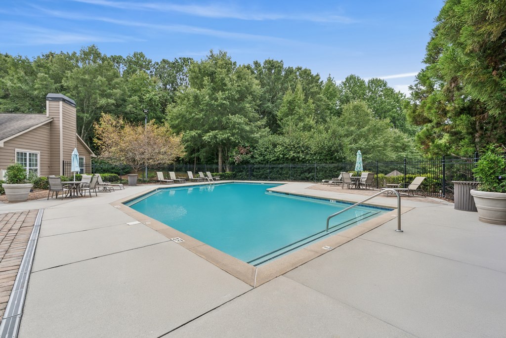 A swimming pool surrounded by trees and a house.