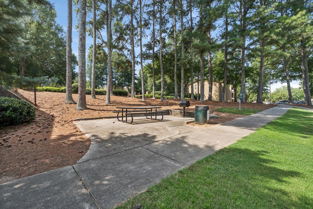 A park with a bench and a trash can.