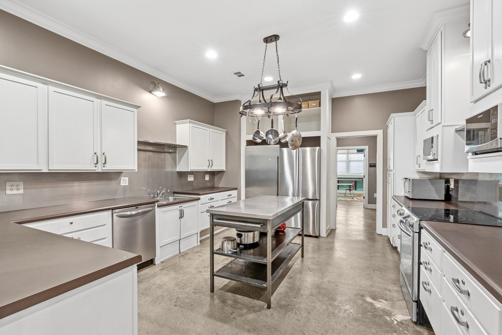 A large, empty kitchen with stainless steel appliances and white cabinets.