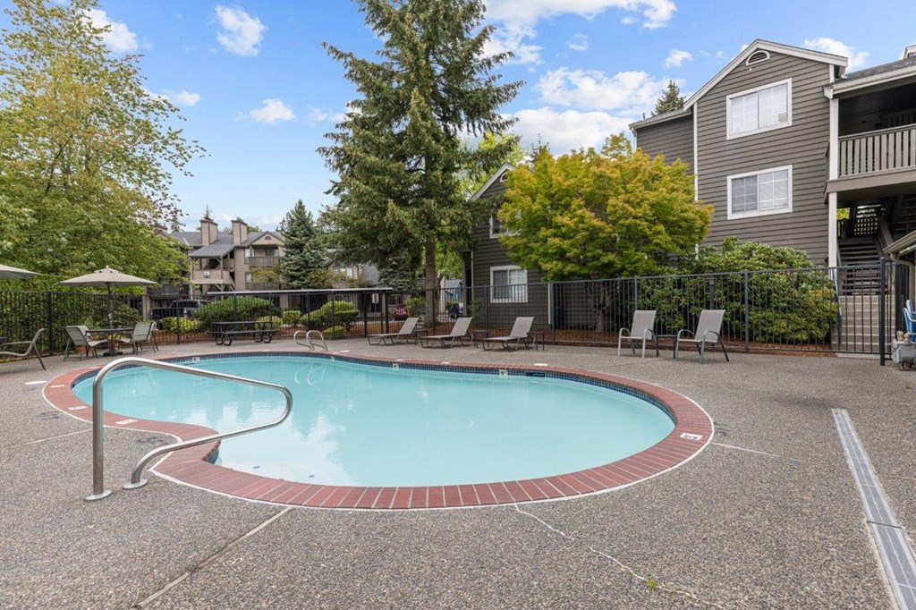 a swimming pool with chairs and a building in the background