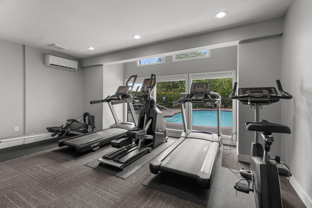 a gym with cardio equipment and a swimming pool