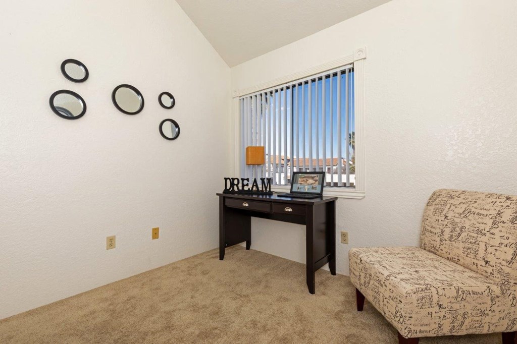 A room with a desk, chair, and mirrors on the wall.