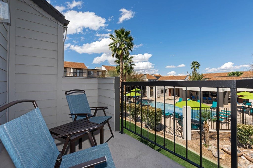 A patio with chairs and a pool in the background.