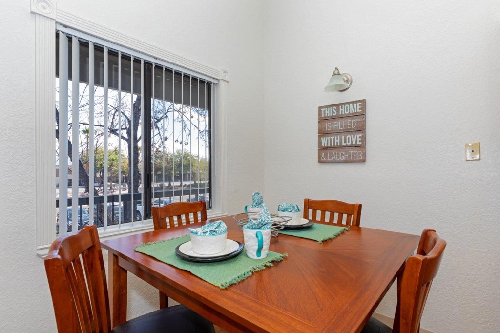 A dining table set with a green placemat and a sign on the wall that says "This home is filled with love and laughter".