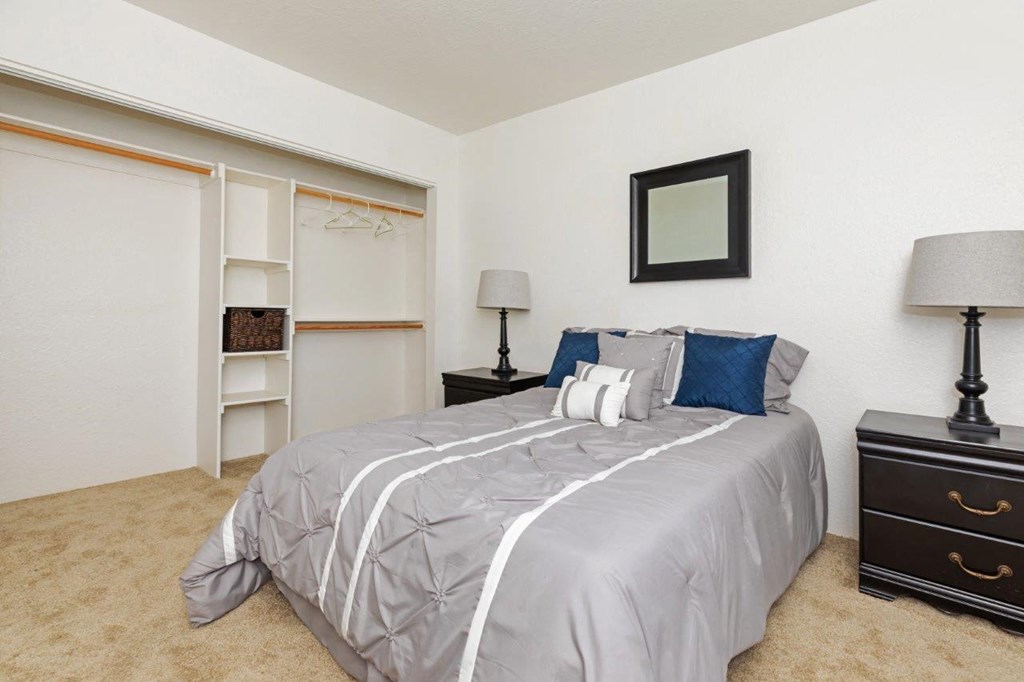 A bedroom with a bed, dresser, and a mirror on the wall.
