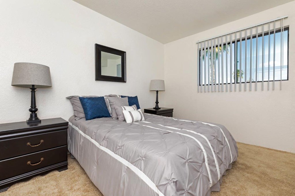 A bedroom with a bed, two lamps, and a picture on the wall.