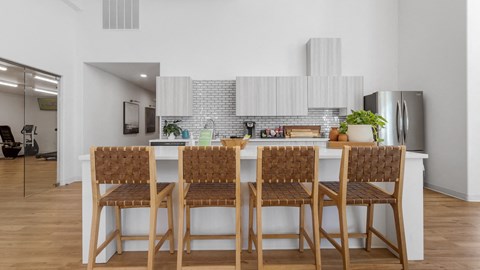 a kitchen with a long island with bar stools in front of a white counter
