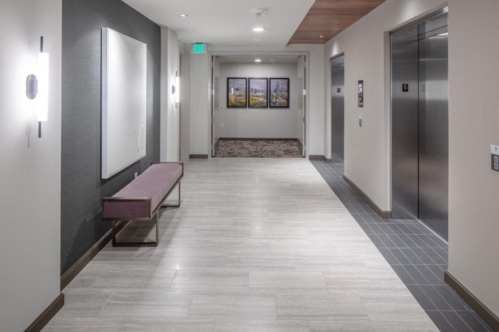 a hallway with a bench and elevators in a building