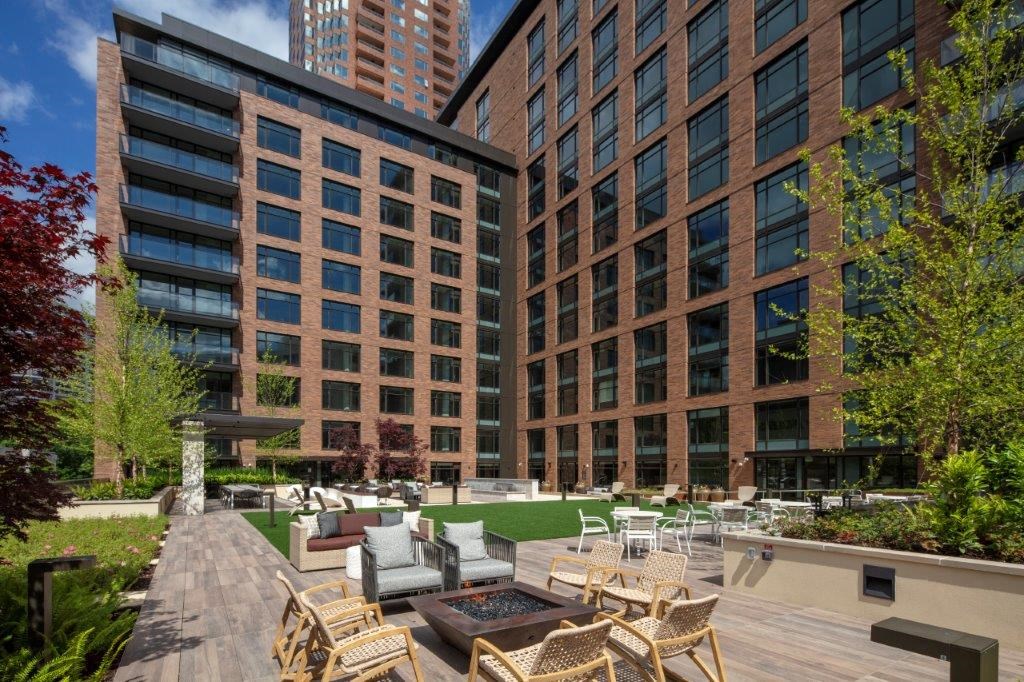 an outdoor patio with chairs and tables in front of a tall building