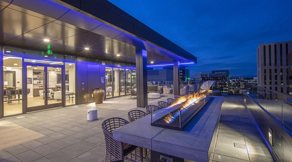 a rooftop terrace with a fireplace and a city at night