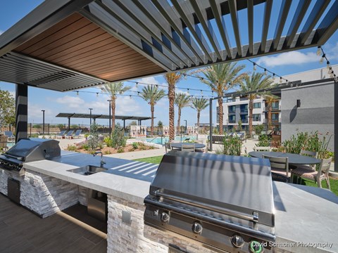A modern outdoor dining area with a long table and chairs under a pergola.