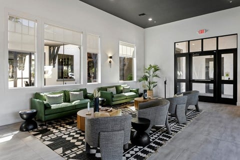 a living room with green couches and chairs and large windows