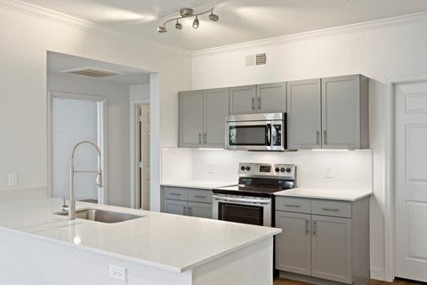 a kitchen with white counter tops and gray cabinets