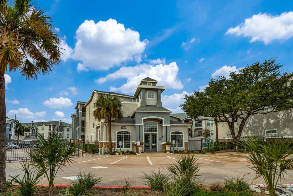 a large building with a parking lot and palm trees