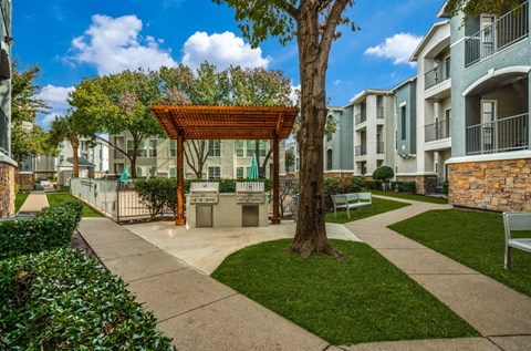 an outdoor patio area with a tree and benches in front of an apartment building