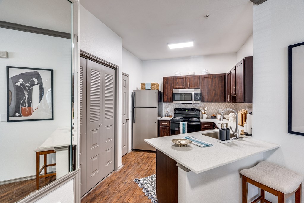 a kitchen with a white counter top and a stainless steel refrigerator