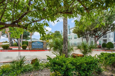a building with a sign in front of trees and plants