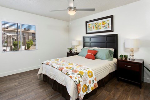 A bedroom with a bed, nightstand, and a painting on the wall.