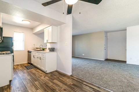A kitchen with white cabinets and a wooden floor.