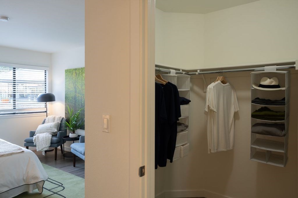 A white bedroom with a white bed and a white chair.