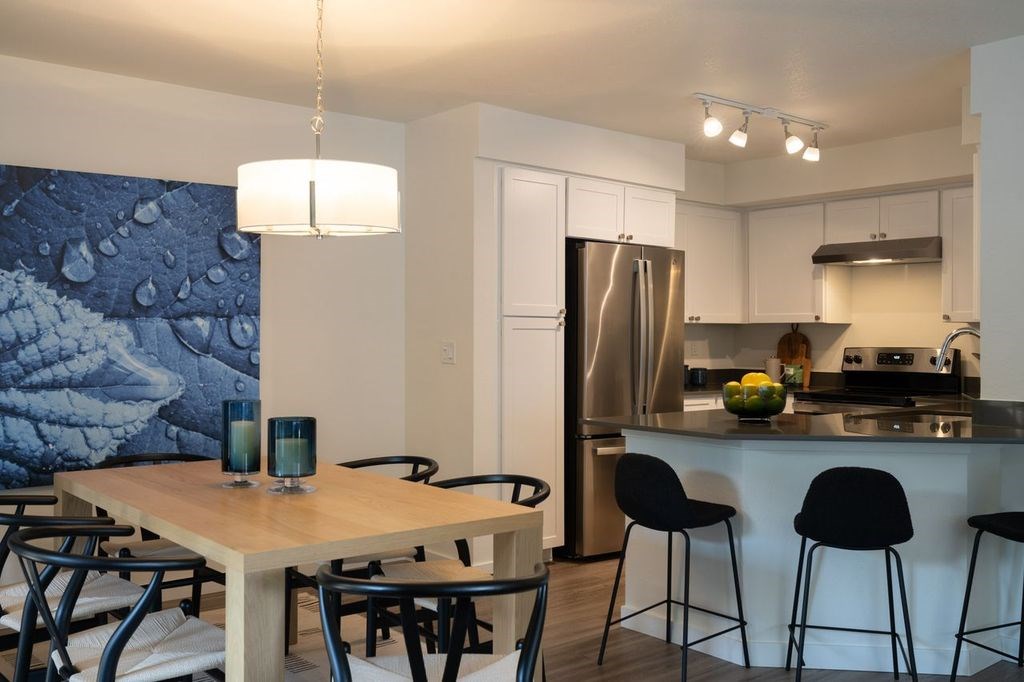 A kitchen with a table and chairs in front of a refrigerator.