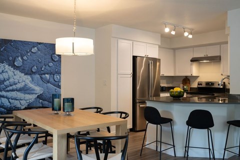 A kitchen with a table and chairs in front of a refrigerator.