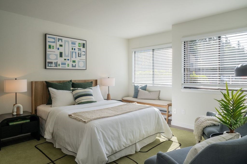 A bedroom with a large bed and a painting on the wall.