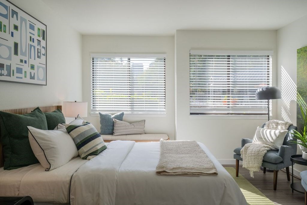 A bedroom with a bed, a chair, and a painting on the wall.