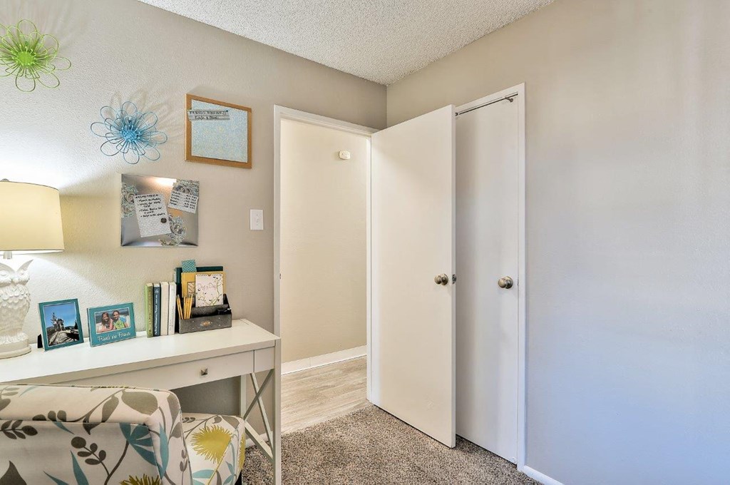 a living room with a desk and a door to a closet