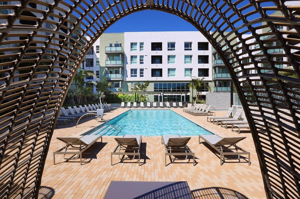 a swimming pool with chairs and a building in the background