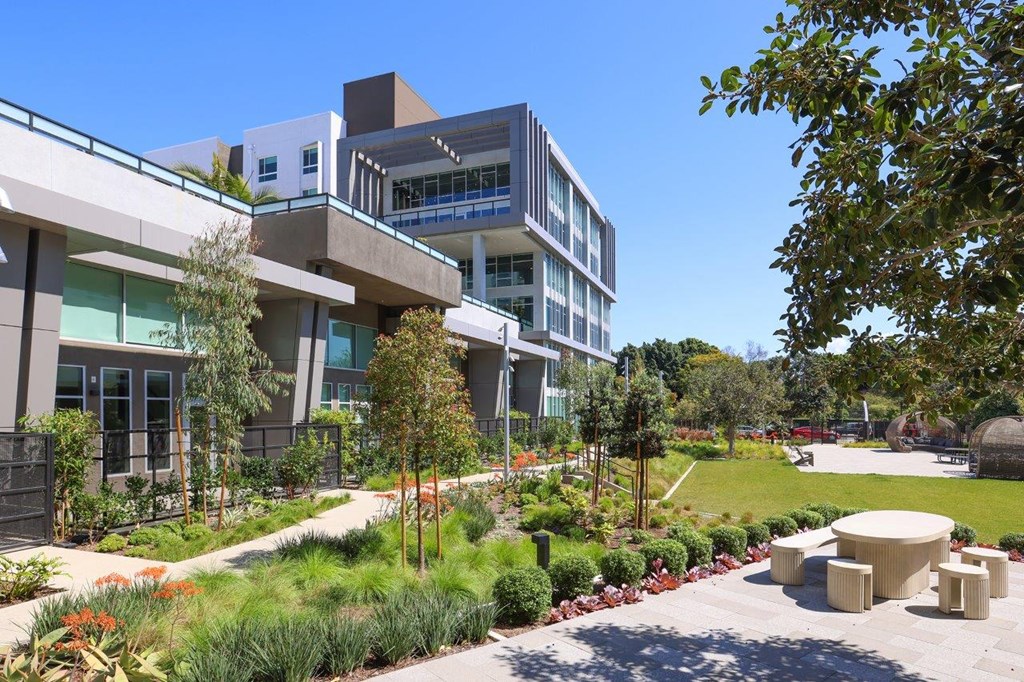 a view of the building with a garden and benches