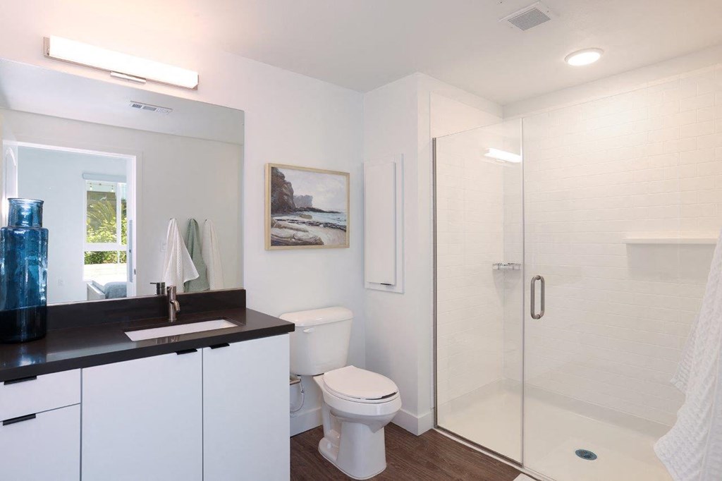 a white bathroom with a toilet and a shower