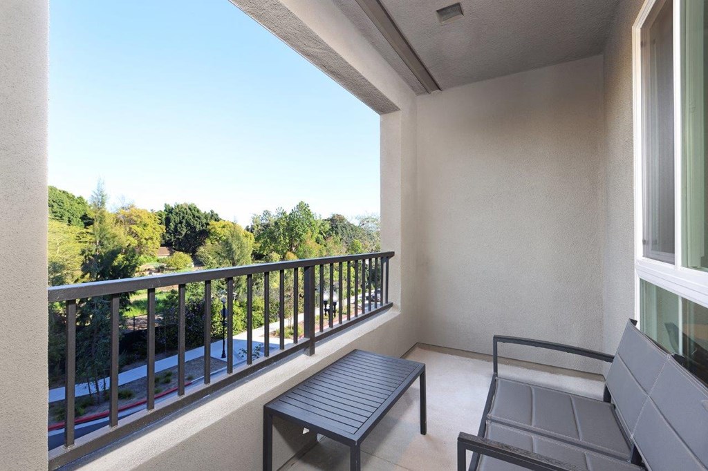 a balcony with a table and chairs and a view of trees